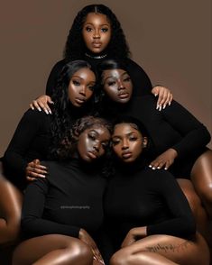 four women in black bodysuits sitting on top of each other with their arms around one another