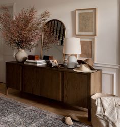 a living room with a large mirror and vases on top of the sideboard