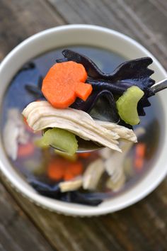 a spoon full of soup with carrots, celery and meat on it