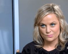 a woman with blonde hair and blue eyes posing for a photo in front of a mirror