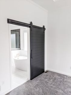 an open door leading to a bathroom with a bathtub in the background and carpet on the floor