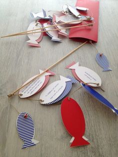 some paper fish are hanging from clothes pins on a table with other items in the background