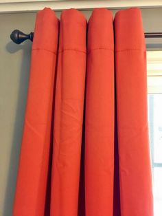 an orange curtain hanging in front of a window