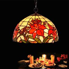 a stained glass lamp hanging over a dining room table with food and candles on it