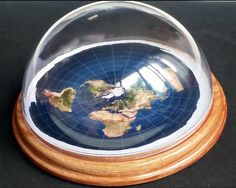 a glass globe on a wooden stand with a black surface and white border around it