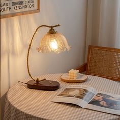 a table with a lamp on top of it next to a magazine and plated food