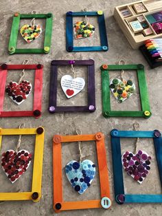 several colorful frames with hearts hanging from them on the floor in front of some books