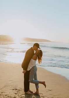 a man and woman kissing on the beach