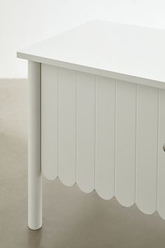 a white table sitting on top of a cement floor next to a metal door handle