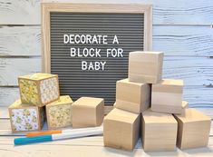 a pile of blocks sitting next to a chalkboard with the words decorate a block for baby written on it