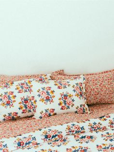 a bed with floral sheets and pillows on it