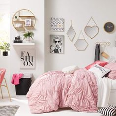 a bedroom with white walls, pink bedding and black and white accessories on the wall