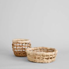 two wicker baskets sitting side by side on a gray surface, one is empty and the other has no handles