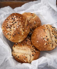 three loaves of bread sitting on top of a piece of wax paper with sesame seeds