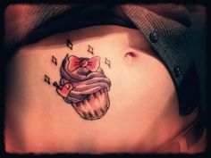 a woman's stomach with a tattoo of a cupcake and a bow on it