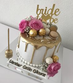 a white and gold wedding cake with pink flowers on the top is decorated with chocolate