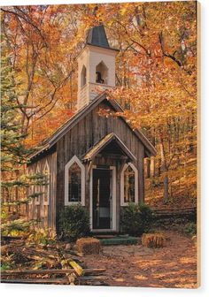 an old wooden church surrounded by trees in the fall