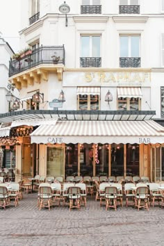 an outdoor cafe with tables and chairs in front of a building on a cobblestone street