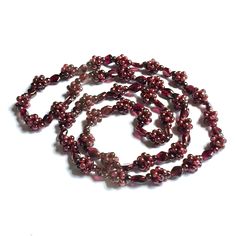 Natural Rhodolite Garnet beads are woven in the beaded ball method alternating with rhombus beads to create this rich berry colored gemstone necklace to slip on overhead. This handmade jewelry necklace looks beautiful on its own or layered with other necklaces in your jewelry collection. We show this worn singly and doubled with a doubling clasp. Garnet is said to be the traveler's gem, offering protection when far from home. Length is 32 inches. Diameter of rope balls are 11.5 mm. Vintage condi Vintage Garnet Jewelry, Garnet Bead Necklace, Garnet Jewelry Necklace, Beaded Ball, Handmade Jewelry Necklace, Garnet Necklace, Gold And Silver Rings, Garnet Jewelry, Hippie Jewelry