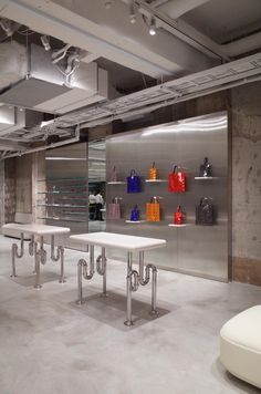 an empty room with several tables and chairs in front of glass shelves filled with purses