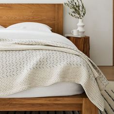 a bed with a white comforter on top of it next to a night stand