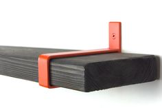 a close up of a wooden shelf with an orange bracket on it's side