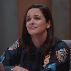 a female police officer sitting at a table in front of a laptop computer and looking off to the side