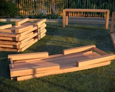 several wooden benches sitting in the grass next to each other