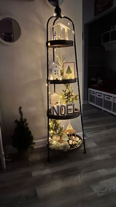 there is a christmas tree with lights on it in the corner of this room, next to a ladder that says noel