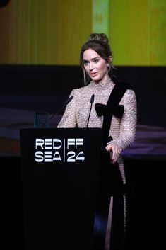 a woman standing at a podium in front of a screen with the words red f seal 24 on it