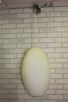 a white lamp hanging from the ceiling in front of a brick wall