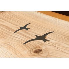 two metal birds sitting on top of a wooden table