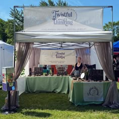 a woman sitting at a table under a tent