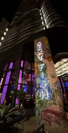 a tall building with many windows and lights on it's sides at night time