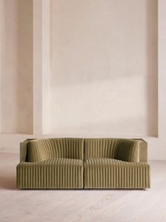 a green couch sitting on top of a wooden floor next to a white wall in an empty room