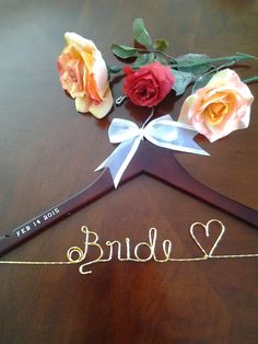 a wedding dress hanger with roses on it and the word love written in cursive writing