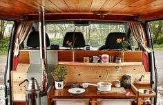 the interior of a van with wood paneling and wooden table in front of it