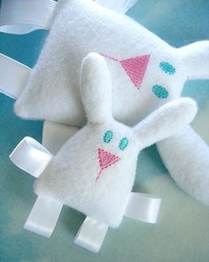 two white stuffed animals with pink and blue designs on them