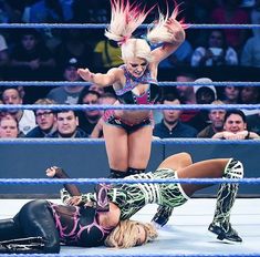 two women wrestling in a ring with one woman on her knees and the other standing up