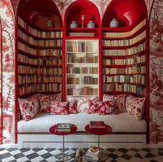 a room with red bookshelves filled with lots of books next to a white couch