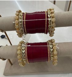 two red and gold bracelets on display in front of a white table with other jewelry items