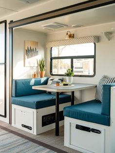 the inside of a camper with two blue seats and a table in front of it