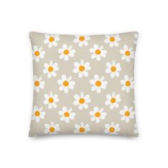 an orange and white pillow with daisies on the front, against a gray background