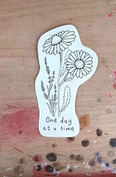 one day at a time sticker on a piece of wood with paint splatters