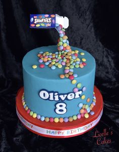 a blue birthday cake with candy sprinkles and an oreo bar on top