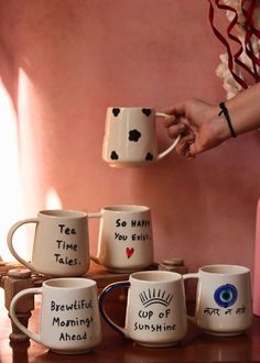 coffee cups with words written on them are being held by a woman's hand