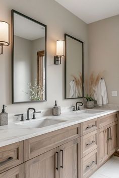 a bathroom with two sinks, mirrors and lights on the wall above them is shown