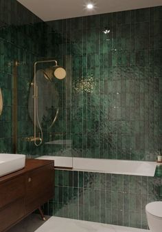 a bathroom with green tiles on the walls and floor, along with a bathtub