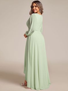 a woman in a long green dress standing with her hands on her hips and looking off to the side