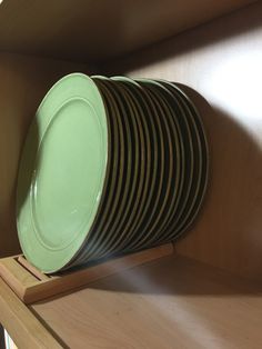 a stack of green plates sitting on top of a wooden shelf